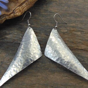 Può includere: Un paio di orecchini triangolari in argento con una texture martellata.