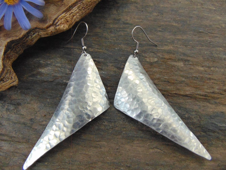 May include: A pair of silver triangle shaped earrings with a hammered texture.