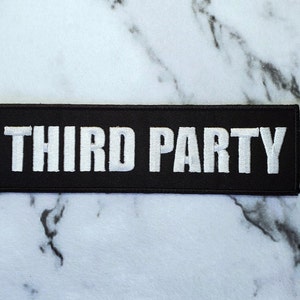 May include: Black fabric patch with white embroidered text that reads "THIRD PARTY".