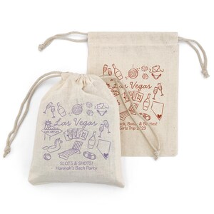 K&ouml;nnte beinhalten: Zwei beige Kordelzugbeutel mit lila und roten Illustrationen zum Thema Las Vegas. Eine Tasche hat den Text "SLOTS & SHOTS! Hannah's Bach Party". Die andere Tasche hat den Text "Girls Trip 2029".