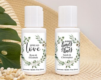May include: Two small white bottles of sunscreen with green foliage designs and personalized text. The left bottle says "Spread Love Ryan & Elizabeth" and the right bottle says "Good Times & Tan Lines Sarah & Christopher".