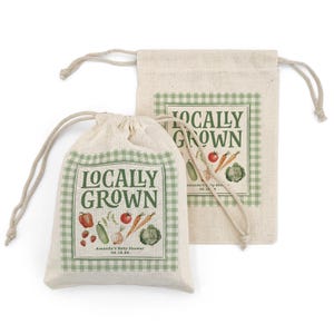 May include: Two beige drawstring bags with a green gingham border and the words "Locally Grown" in a vintage font. The bags feature illustrations of vegetables like tomatoes, carrots, and cabbage. The text "Amanda's Baby Shower 08.19.20" is also visible.