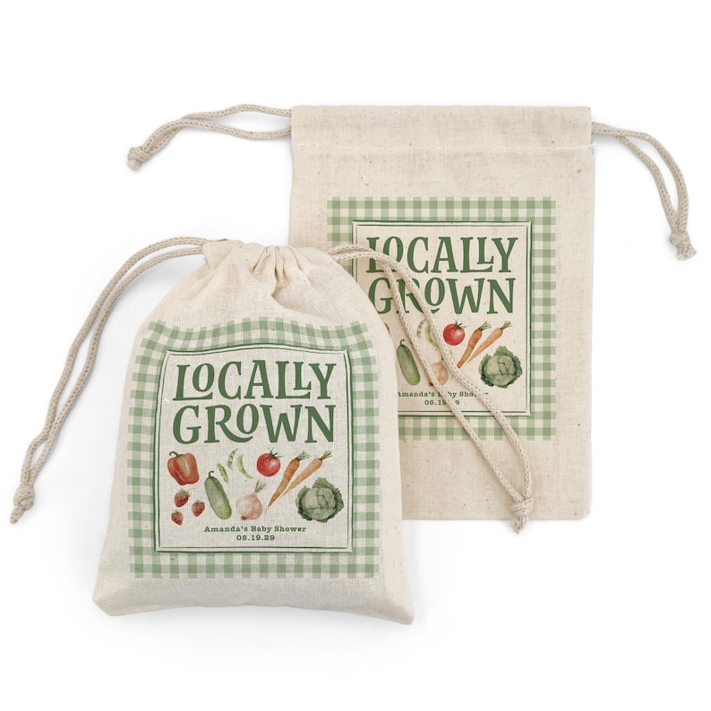 May include: Two beige drawstring bags with a green gingham border and the words "Locally Grown" in a vintage font. The bags feature illustrations of vegetables like tomatoes, carrots, and cabbage. The text "Amanda's Baby Shower 08.19.20" is also visible.