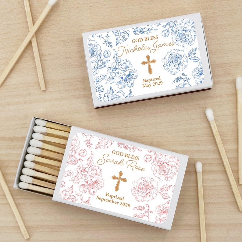Puede incluir: Dos cajas de cerillas con dise&ntilde;os florales y texto personalizado. Una caja presenta patrones florales azules y el texto "God Bless Nicholas James", una cruz y "Bautizado mayo de 2029". La otra caja tiene patrones florales rosas y dice "God Bless Sarah Rose", una cruz y "Bautizado septiembre de 2029".