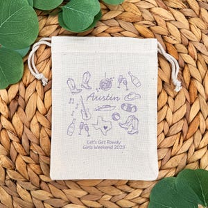 5" x 7" cotton drawstring bags printed with hand drawn Austin icons including cowboy boots, disco ball, boat, and a guitar along with two lines of personalized text.