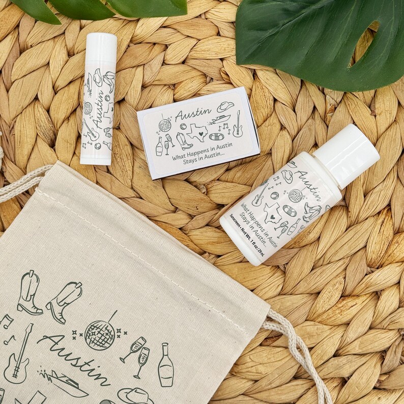 May include: A collection of Austin-themed items, including a lip balm, a small box, a sunscreen bottle, and a drawstring bag. The items are decorated with illustrations of boots, guitars, and the text "What Happens in Austin Stays in Austin..."