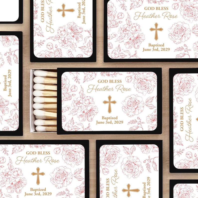 Puede incluir: Cajas de cerillas con un dise&ntilde;o floral y el texto "GOD BLESS Heather Rose" y "Baptized June 3rd, 2029". El dise&ntilde;o incluye una cruz e ilustraciones florales en una paleta de colores suaves. La caja de cerillas es negra.