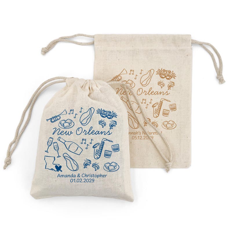 May include: Two beige drawstring bags with New Orleans themed illustrations. One bag has blue drawings, including a map, musical notes, and food. The other bag has brown drawings. Text includes "New Orleans" and names with a date.