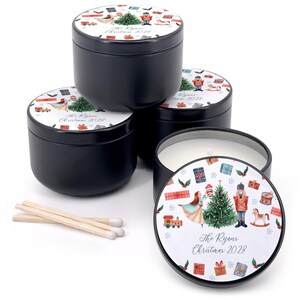 May include: Black metal candle tins with decorative lids featuring a Christmas theme. The lids display a Christmas tree, nutcracker, and other festive illustrations. The text "The Ryans Christmas 2028" is also visible. Matches are included.