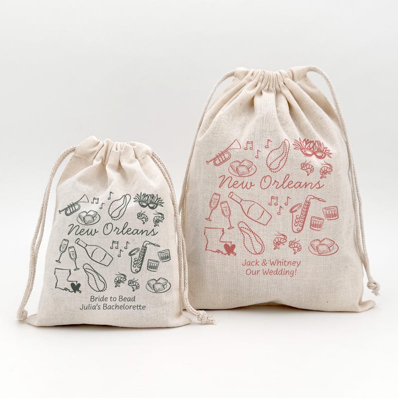 Two drawstring bags (5" x 7" and 8" x 10") with green and pink New Orleans themed illustrations. Both bags offer two lines of custom text and have a variety of New Orleans themed illustrations including beads, bourbon, music, and mardi gras mask.
