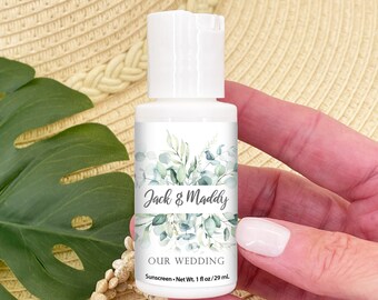 May include: White plastic bottle of sunscreen with a green leafy design and the text "Jack & Maddy Our Wedding Sunscreen - Net Wt. 1 fl oz/29 mL"