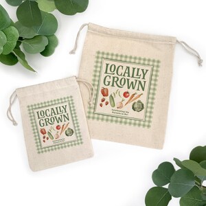 May include: Two beige drawstring bags with a green gingham border and the words "Locally Grown" printed on them. The bags feature illustrations of vegetables and the text "Celebrating the Parents to Be!"
