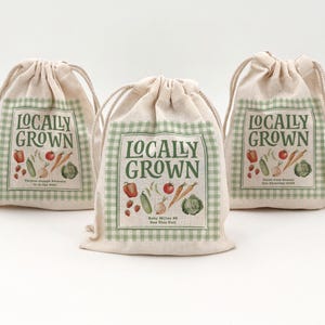 Three beige drawstring bags (5" x 7") with text and graphics. The bags say Locally Grown, have water colored veggies and fruit, and also have a green and cream checkered border.  Text includes names and baby shower dates.