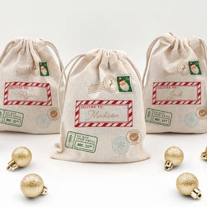 Three mini drawstring bags designed as a Santa sack with a Santa stamp, Do Not Open till Christmas stamp, and a checked twice stamp.  Personalized with a red stripe box and first name in gold.