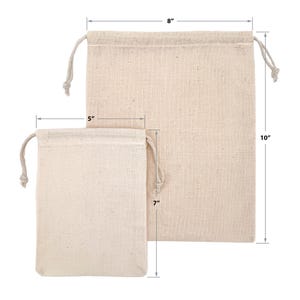 May include: Two beige canvas drawstring bags. The larger bag is 10 inches tall and 8 inches wide. The smaller bag is 7 inches tall and 5 inches wide. Both bags have a drawstring closure at the top.