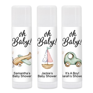 May include: Three white lip balm tubes with "oh Baby!" in script. Each tube features a different watercolor illustration: an airplane, a sailboat, and a car. Text below reads "Samantha's Baby Shower", "Jackie's Baby Shower", and "It's A Boy! Sarah's Showe".