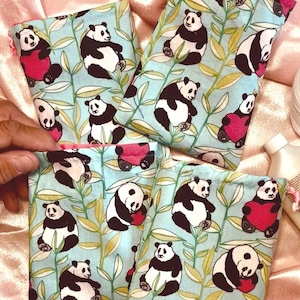May include: Four rectangular fabric pouches featuring a light blue background with a repeating pattern of black and white pandas, some holding red hearts, interspersed with green bamboo leaves. Each pouch has a drawstring closure at the top.