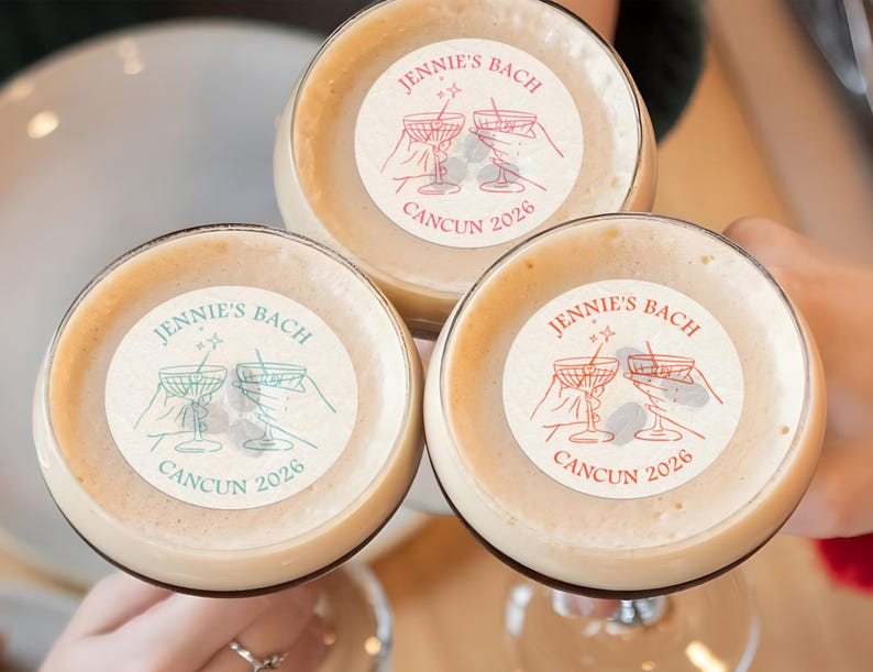 May include: Three clear glass cups with a beige liquid inside. Each cup has a round sticker with the text "JENNIE'S BACH CANCUN 2026" and a graphic of two martini glasses with stars above them.