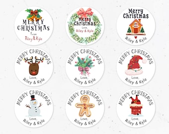 May include: A collection of nine round Christmas stickers with various festive designs. Each sticker features the text "Merry Christmas" and "Love, Riley & Kyle." Designs include bells, wreaths, a gingerbread house, a reindeer, a Santa hat, a snowman, a gingerbread man, and Santa in a chimney.