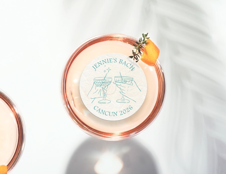 May include: A white round sticker with a teal design of two martini glasses with a star and a line above them. The text on the sticker reads "Jennie's Bach Cancun 2026".