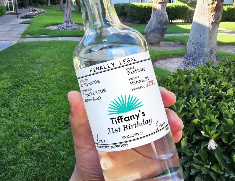 May include: A clear glass bottle of tequila with a white label that says "Finally Legal" and "Tiffany's 21st Birthday". The label also includes the text "Proyecto 06-03-2004", "Clase Birthday", "Hecho Miami, FL", "Numero 2026", "Tequila 100% Agave Azul", "Exclusivo", and "ALC VOL (80 PROOF)".