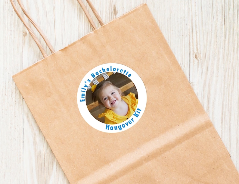 Op de afbeelding: Een ronde sticker met een witte achtergrond en blauwe tekst. De tekst luidt "Emily's Bachelorette Hangover Kit". In het midden van de sticker staat een foto van een jong meisje in een geel shirt.