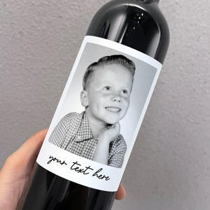 May include: A black and white photo of a young boy with a checkered shirt is on a wine bottle label. The label has the text "your text here" written on it.