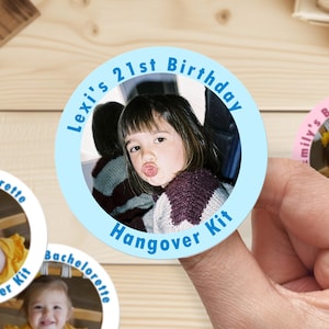 Op de afbeelding: Ronde blauwe en witte sticker met een foto van een jong persoon en de tekst "Lexi's 21st Birthday Hangover Kit".