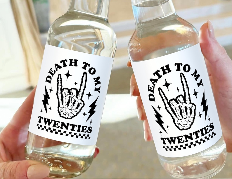 May include: Two clear glass bottles with white labels that say "Death to my twenties" in black text. The labels also feature a black and white illustration of a skeleton hand making a rock and roll hand gesture.