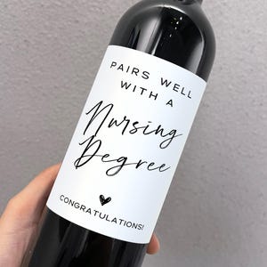 May include: A bottle of red wine with a white label that says "Pairs well with a Nursing Degree. Congratulations!"