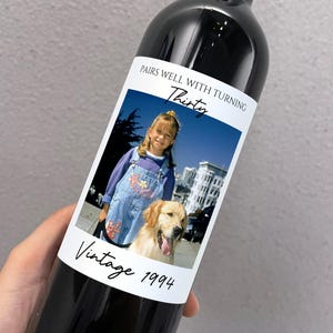 May include: A dark wine bottle with a custom label featuring a photo of a young girl and a golden retriever. The label reads "Pairs Well With Turning Thirty" and "Vintage 1994."