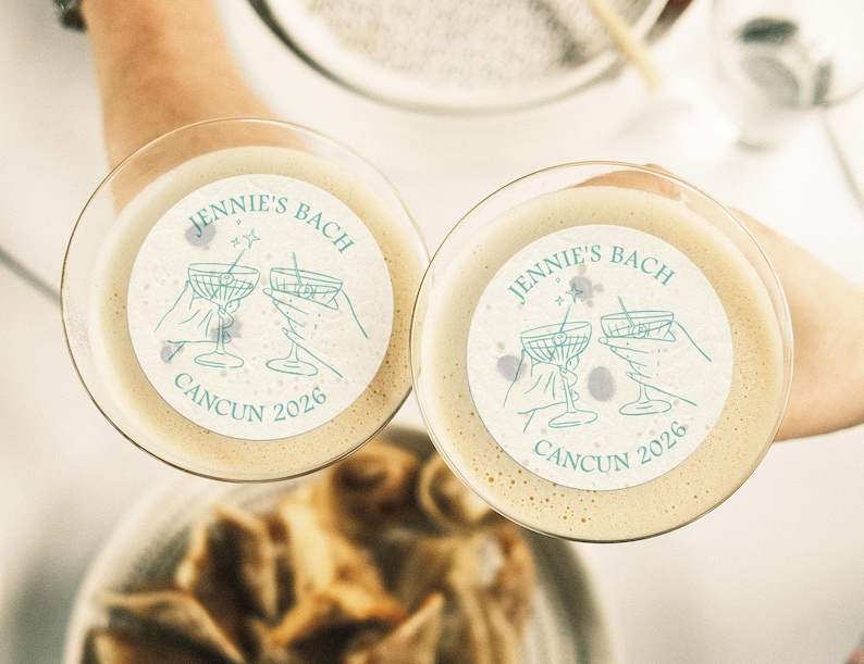 May include: Two white cocktail coasters with a blue design of two martini glasses clinking together. The text on the coasters reads "Jennie's Bach Cancun 2026".