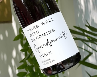 May include: A white wine bottle with a black label that reads "Pairs well with becoming grandparents again". The label also includes the text "Baby Mike coming 2025".