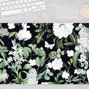 May include: A black background with a repeating pattern of white flowers and green leaves. The flowers are various types of white blossoms, including roses, peonies, and lilies. The leaves are a deep green and have a slightly textured appearance.