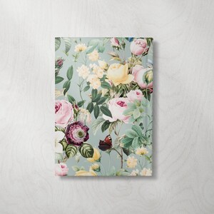 May include: A rectangular notebook with a floral design. The cover features a light blue background with a pattern of pink, yellow, and purple roses, green leaves, and a butterfly. The notebook is a decorative item.
