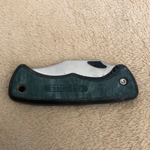 May include: A green and silver folding pocket knife with the words "G.I. HUNTER" on the handle.