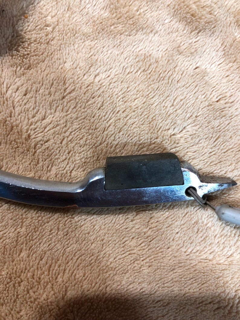 May include: A silver metal can opener with a black rubber grip. The opener has a small hole in the handle for hanging.