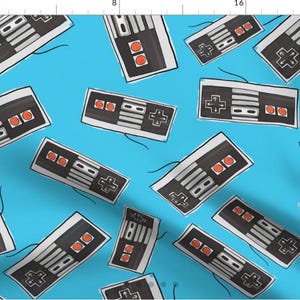 May include: A seamless pattern featuring a repeating design of retro video game controllers on a bright blue background. The controllers are black and gray with red buttons.