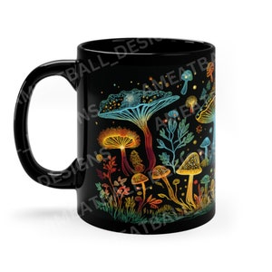 May include: Black ceramic mug with a colorful mushroom design. The mushrooms are drawn in a psychedelic style with glowing colors and intricate details. The background is black with a subtle starry pattern.