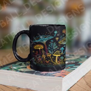 May include: Black ceramic mug with a colorful mushroom design. The mushrooms are drawn in a whimsical style with glowing details. The mug is sitting on a stack of books.