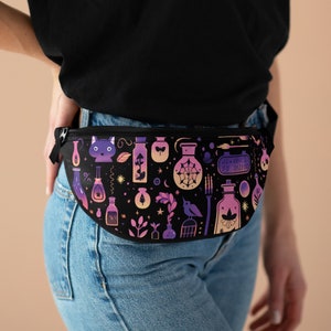 May include: A black fanny pack with a colorful print of potion bottles, a cat, a bird, and other magical elements. The text on the pack reads "Je Veux Du Boo Boo Off Off".
