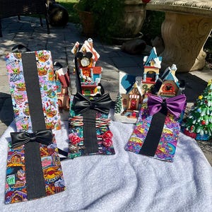 May include: Four colorful fabric pouches with black ribbon bows and black elastic straps. Each pouch has a different pattern, including a Star Wars theme, a candy cane theme, a rainbow theme, and a Harry Potter theme.