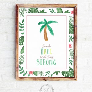 May include: A framed print with a watercolor illustration of a palm tree and the text "stand tall and stay strong". The frame has a green and pink tropical leaf border.