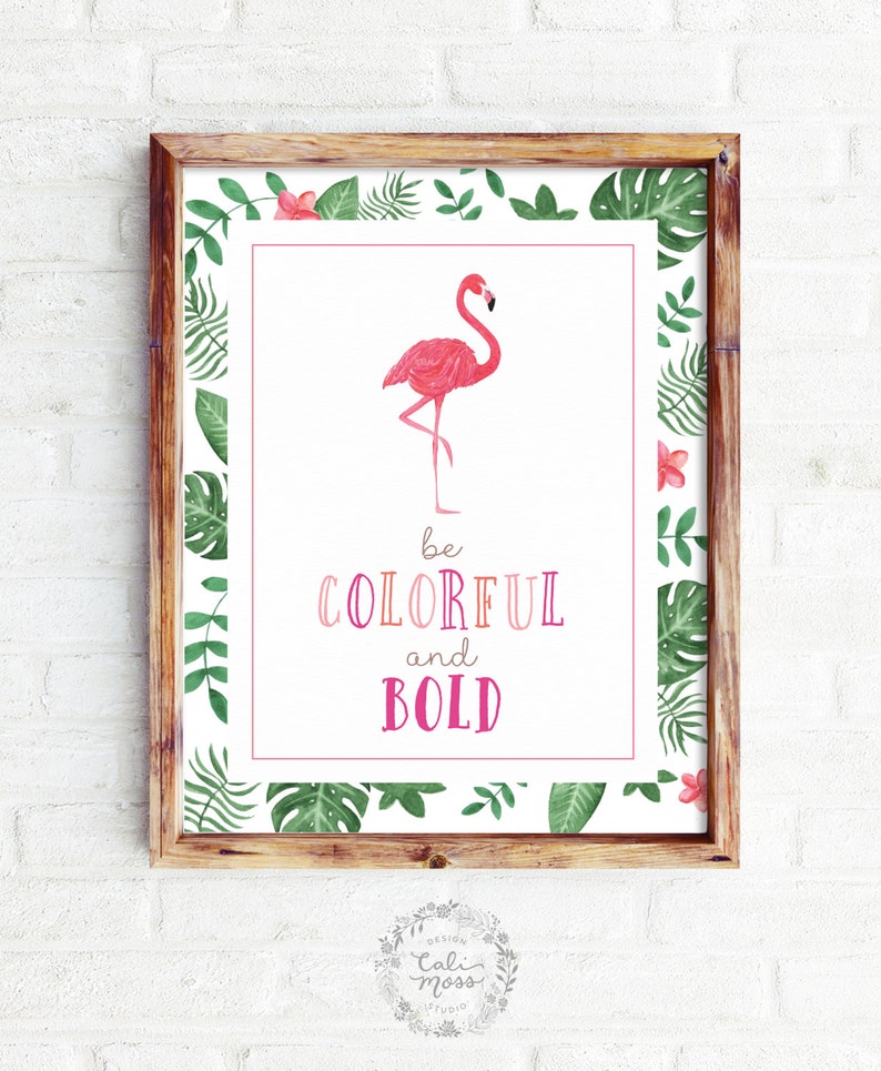 May include: A framed print with a pink flamingo illustration and the text "be colorful and bold" surrounded by green tropical leaves.