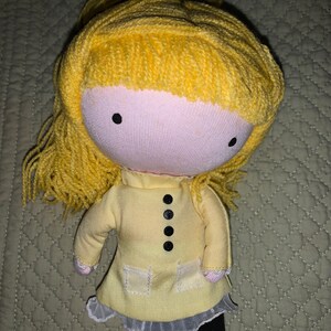 May include: A yellow handmade doll with long yellow yarn hair, a yellow dress with black buttons, and black leggings.