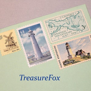 Op de afbeelding: Een verzameling vintage Amerikaanse postzegels met een vuurtoren, een windmolen en een kaart van Annapolis, Maryland. De postzegels zijn in verschillende kleuren, waaronder blauw, groen, geel en rood.