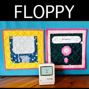 May include: A quilt pattern with two floppy disk blocks and three layouts in three sizes. The word "FLOPPY" is at the top. The pattern includes a miniature computer and the text "BE POSITIVE". Designed by Karin Pudenz.
