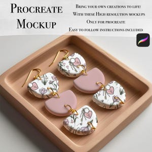 Puede incluir: Pendientes en forma de corazón con ganchos dorados y un diseño floral y de cerradura. Los pendientes se muestran en una bandeja de madera. El texto "PROCREATE MOCKUP" está incluido.