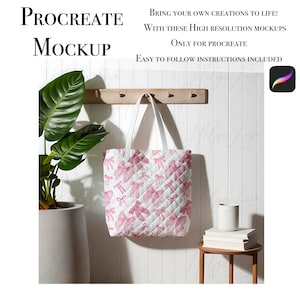 Puede incluir: Una bolsa de tela blanca con un patrón de lazos rosas colgando de un estante de madera. La bolsa está delante de una pared blanca con una planta en maceta a la izquierda y una pequeña mesa de madera con libros y una taza blanca a la derecha. El texto "PROCREATE MOCKUP" está en la parte superior de la imagen.