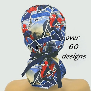 May include: A blue and white patterned scrub cap featuring Spider-Man. The cap has a dark blue ribbon and the text "over 60 designs" in black.